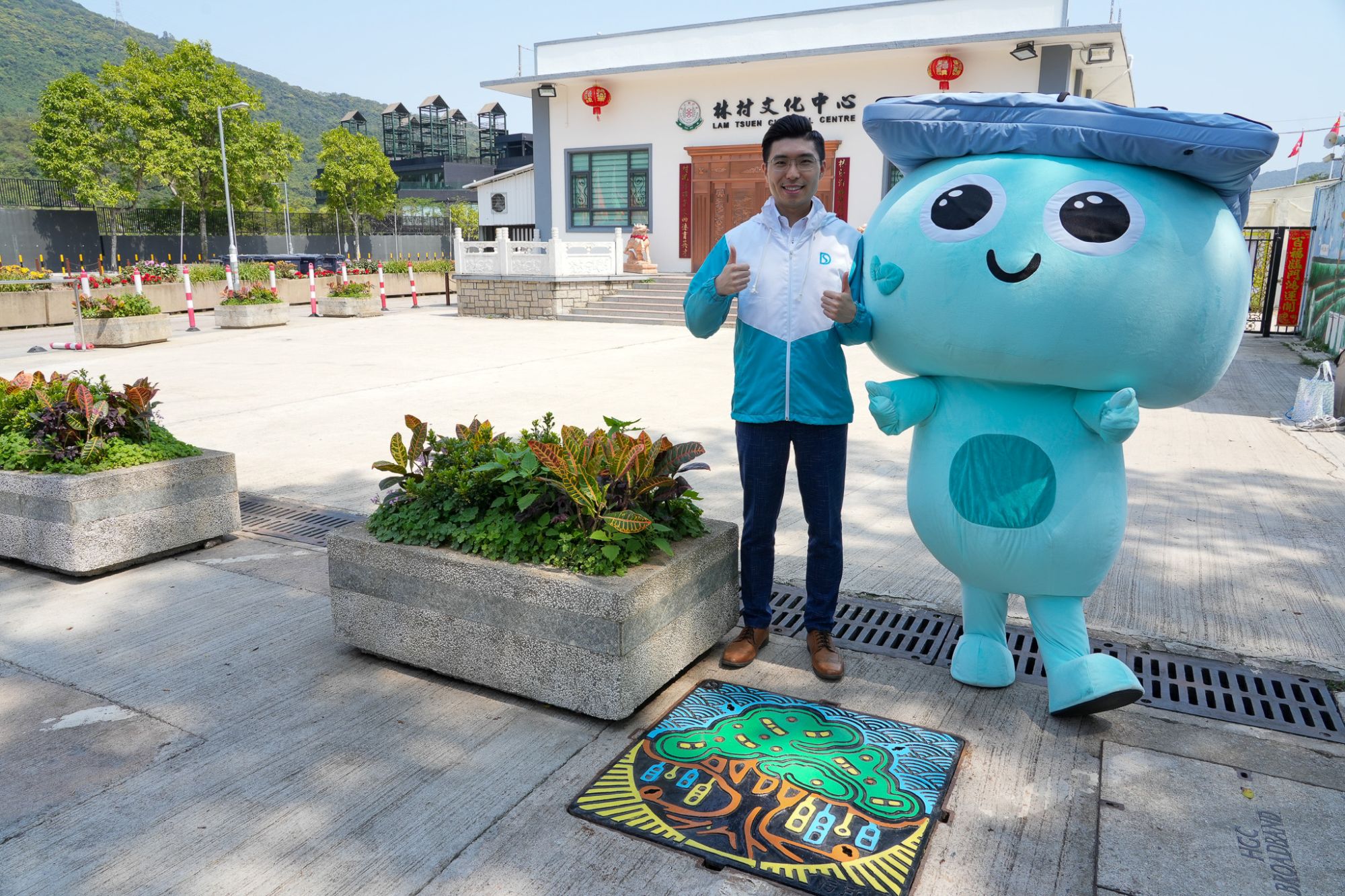 Mr CHAN Yu Kwan, Engineer (Mainland North Division) of the DSD (left) and Drainy, the DSD’s KOL (right), introduces the thematic manhole covers located on Lam Tsuen Heung Kung Sho Road and near Lam Tsuen Wishing Square.
