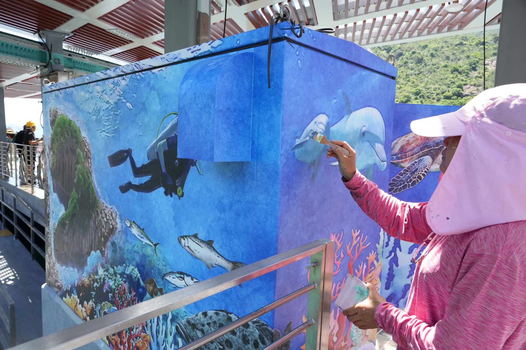 A villager paints beautiful pictures on pillar boxes, adding colour and local sentiment to the pier.